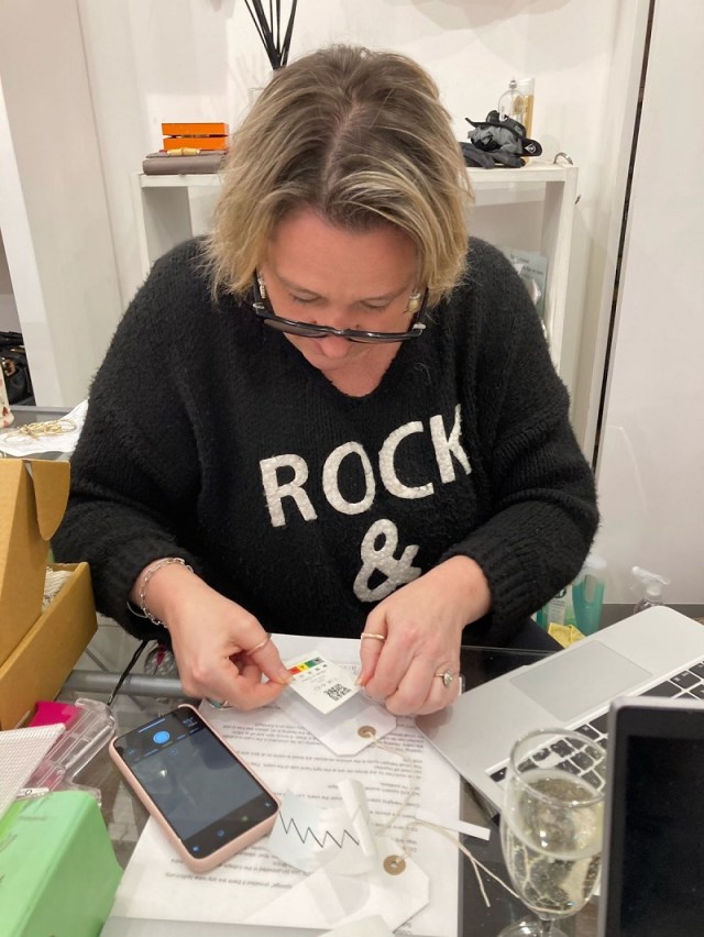 Image of Carrie at work applying one of the stickers to a product's label.