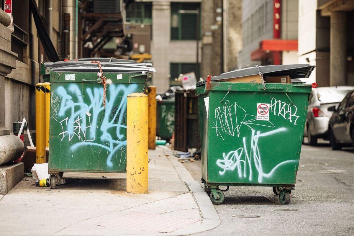 Two green dumpsters next to each other.