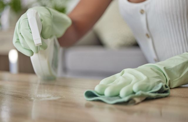 Person with gloves on is cleaning the counter.